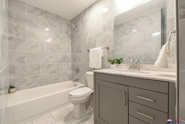 full bath with toilet, shower / bathtub combination, marble finish floor, vanity, and tile walls