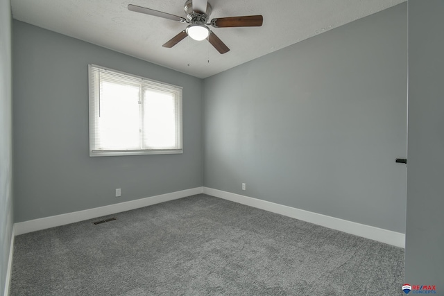 carpeted spare room featuring a ceiling fan, visible vents, and baseboards