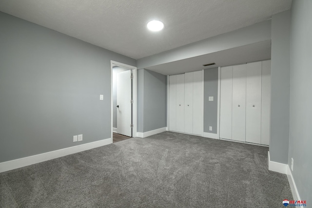 spare room with baseboards, visible vents, dark carpet, and a textured ceiling