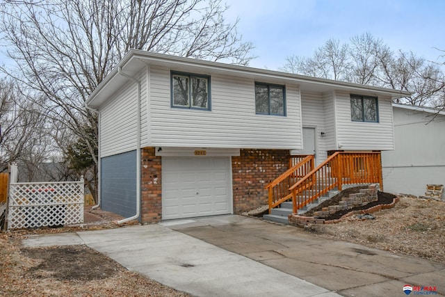 bi-level home with a garage, driveway, and brick siding