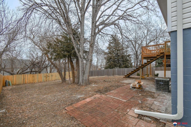 view of yard with a fenced backyard, stairs, central AC, and a patio