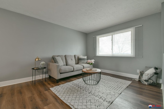 living room featuring a textured ceiling, dark wood-type flooring, and baseboards