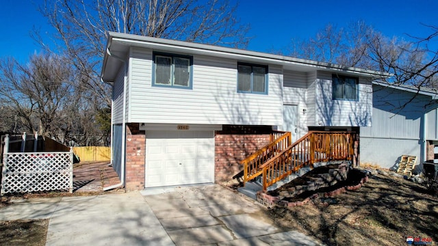 view of front of home featuring brick siding, concrete driveway, stairway, fence, and a garage