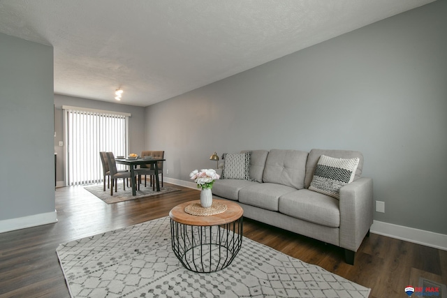 living area featuring a textured ceiling, baseboards, and dark wood-type flooring