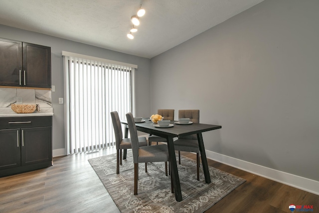 dining room with lofted ceiling, baseboards, and dark wood-type flooring