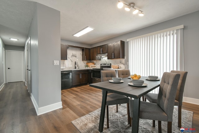 kitchen featuring wood finished floors, stainless steel range with electric cooktop, black dishwasher, light countertops, and dark brown cabinets