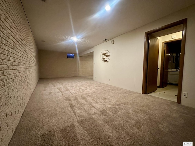 empty room featuring brick wall, visible vents, and light colored carpet