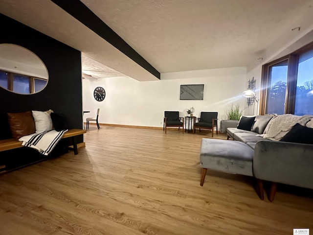 living area featuring beamed ceiling, wood finished floors, and baseboards