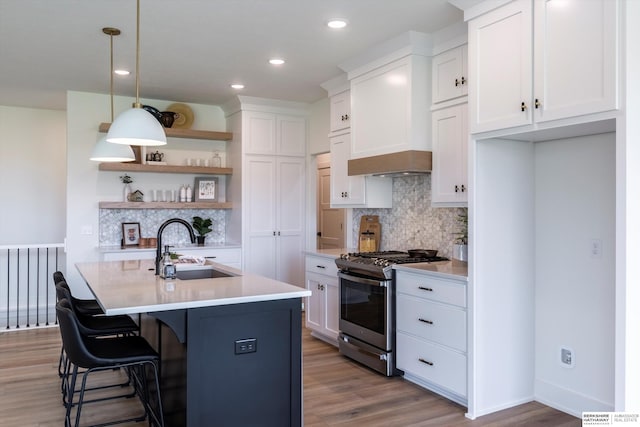 kitchen featuring stainless steel gas stove, white cabinets, light countertops, and a sink