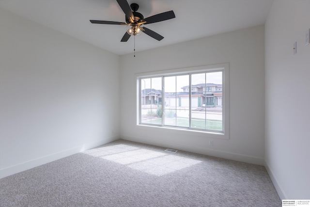 empty room featuring visible vents, baseboards, a ceiling fan, and light colored carpet