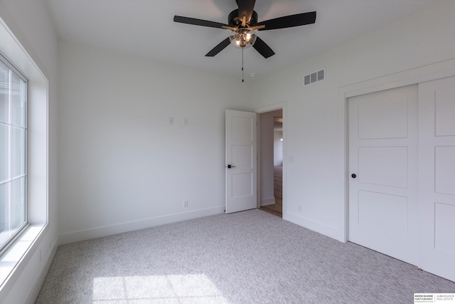 unfurnished bedroom featuring light carpet, multiple windows, a closet, and visible vents