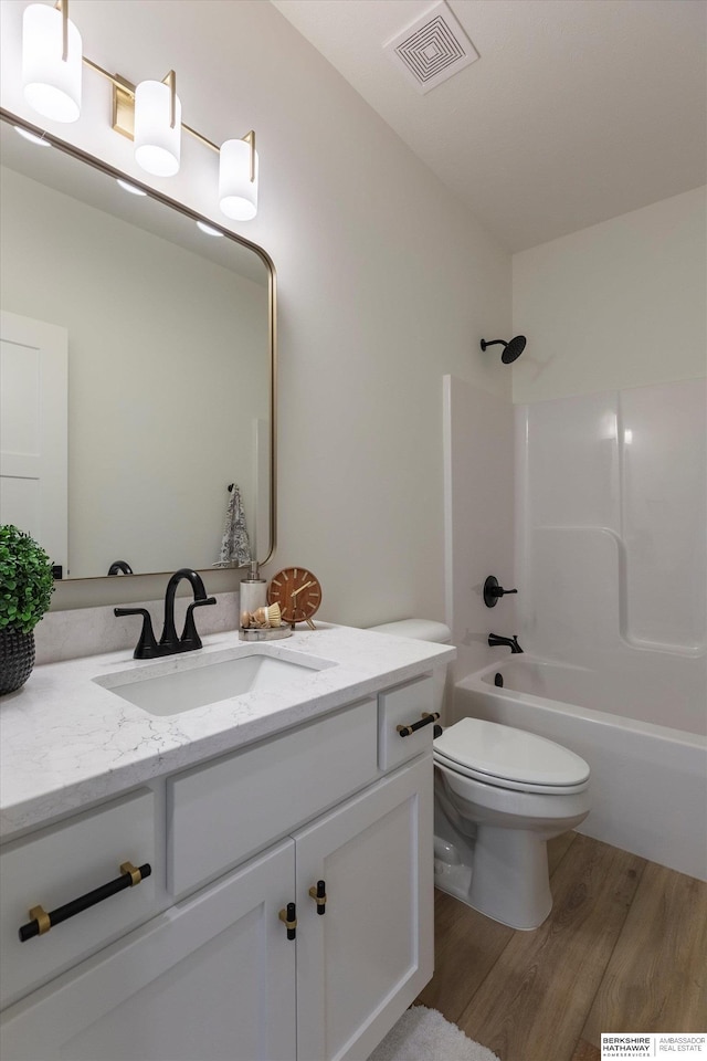 bathroom featuring shower / bathtub combination, toilet, wood finished floors, vanity, and visible vents