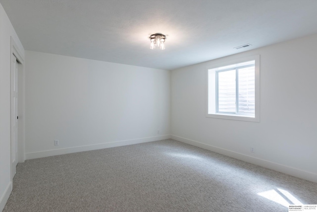 carpeted spare room featuring visible vents and baseboards