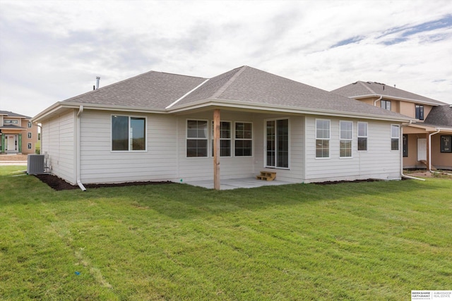 rear view of house featuring a yard, central AC unit, roof with shingles, and a patio area