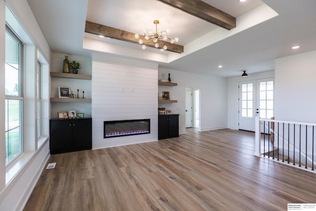 unfurnished living room featuring a fireplace, wood finished floors, visible vents, baseboards, and beamed ceiling