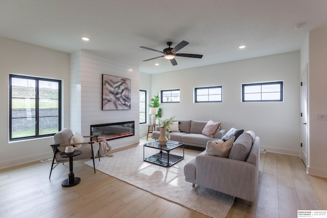 living area with recessed lighting, baseboards, a fireplace, and light wood finished floors