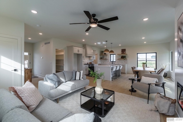 living area featuring a ceiling fan, recessed lighting, visible vents, and light wood-style flooring