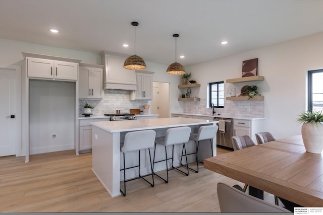 kitchen with dishwasher, a kitchen island, decorative light fixtures, light countertops, and open shelves