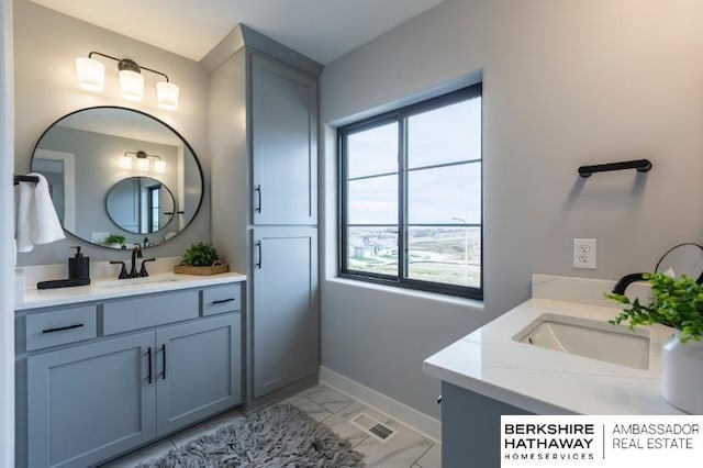 full bath featuring two vanities, a sink, visible vents, and baseboards