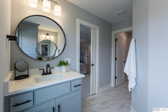 ensuite bathroom featuring ensuite bathroom, vanity, visible vents, baseboards, and marble finish floor