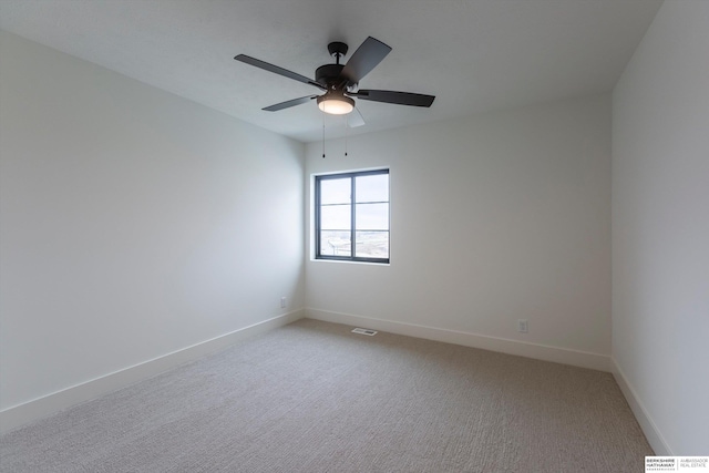 spare room with light carpet, ceiling fan, visible vents, and baseboards