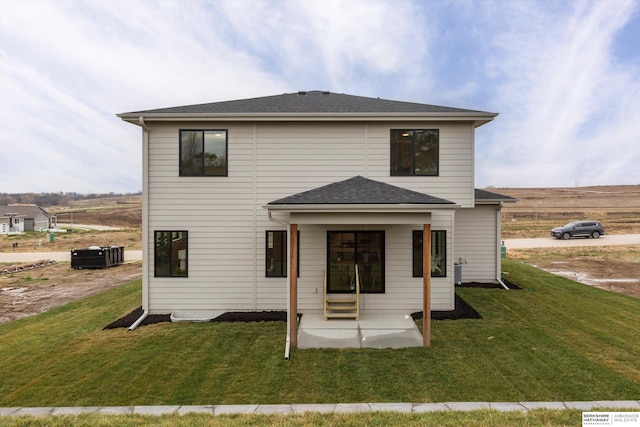 back of property with a yard, a shingled roof, a patio area, and central air condition unit