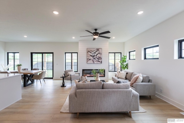 living room with recessed lighting, a fireplace, light wood-style flooring, and a healthy amount of sunlight