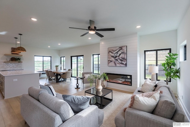 living area featuring light wood-style floors, recessed lighting, a large fireplace, and ceiling fan