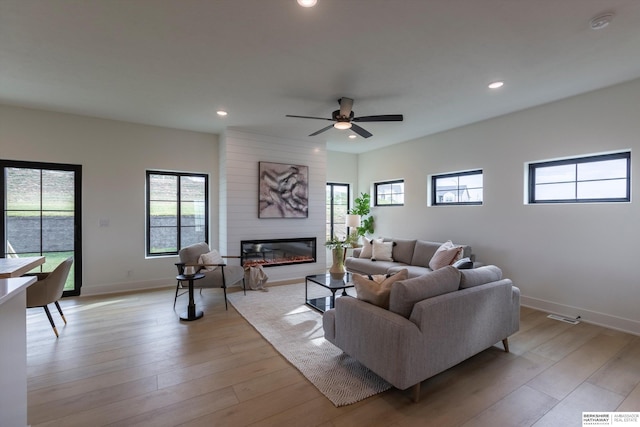 living room with recessed lighting, a large fireplace, a ceiling fan, baseboards, and light wood-type flooring