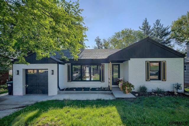 view of front of property featuring a garage, a front yard, concrete driveway, and brick siding