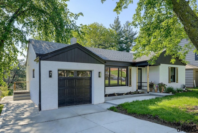 view of front of home with a garage, brick siding, a shingled roof, concrete driveway, and a chimney