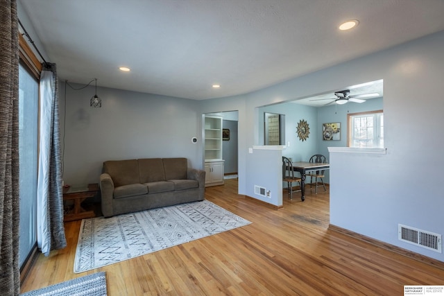 living room with light wood-type flooring, visible vents, a ceiling fan, and recessed lighting