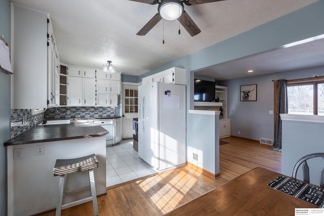 kitchen featuring white appliances, visible vents, white cabinetry, open shelves, and dark countertops