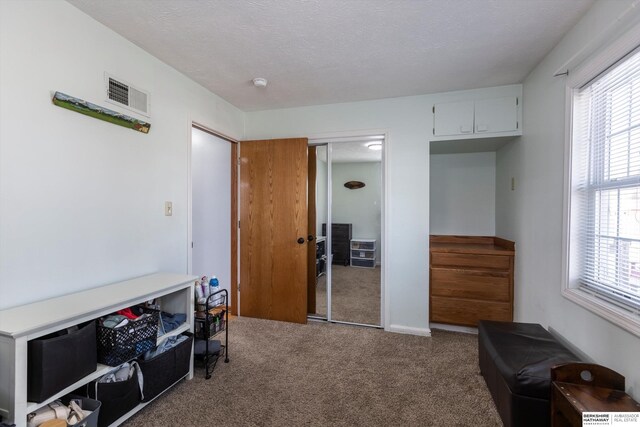 interior space with a textured ceiling, carpet floors, a closet, and visible vents