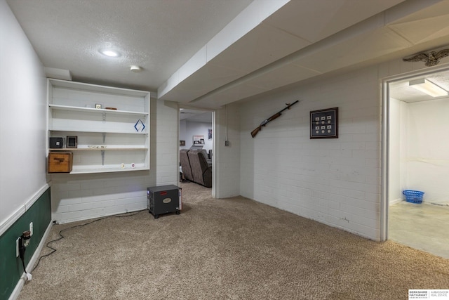 finished basement with brick wall, a textured ceiling, and light colored carpet