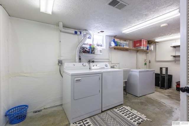 clothes washing area with laundry area, visible vents, separate washer and dryer, and a textured ceiling