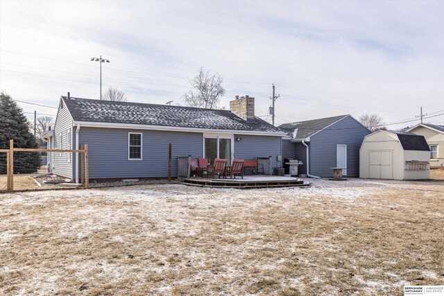 rear view of house featuring a storage shed, a chimney, an outbuilding, fence, and a wooden deck
