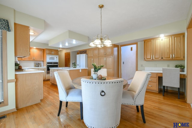 dining space with visible vents, a notable chandelier, built in study area, and light wood finished floors