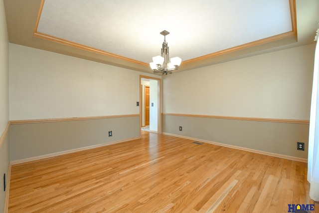 unfurnished room featuring a notable chandelier, light wood-style flooring, baseboards, and ornamental molding