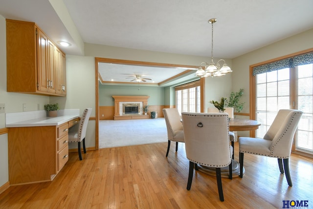 dining room with light wood finished floors, crown molding, a notable chandelier, a glass covered fireplace, and built in study area