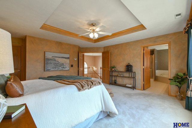 bedroom featuring visible vents, light colored carpet, ensuite bath, and a tray ceiling