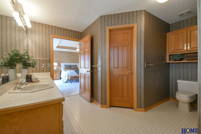 ensuite bathroom with baseboards, wallpapered walls, double vanity, a sink, and ensuite bathroom