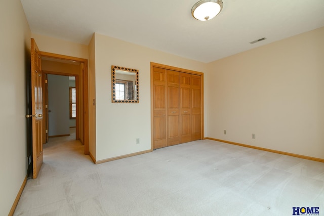 unfurnished bedroom featuring baseboards, visible vents, a closet, and light carpet