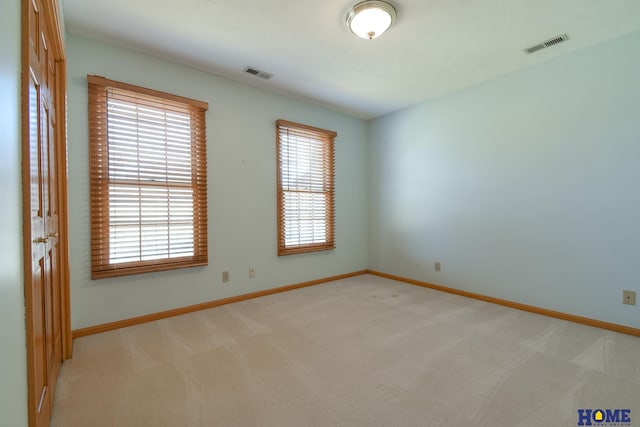 spare room with plenty of natural light, visible vents, and light carpet