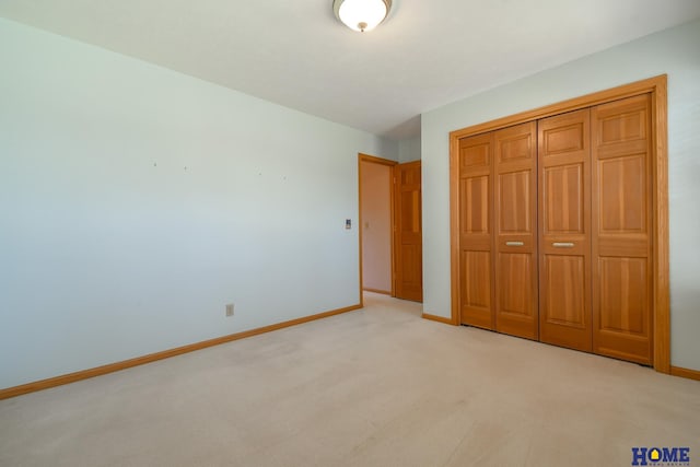 unfurnished bedroom featuring light carpet, a closet, and baseboards