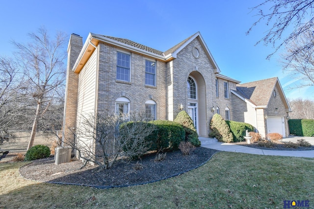 view of front of house with cooling unit, concrete driveway, a front yard, brick siding, and a chimney