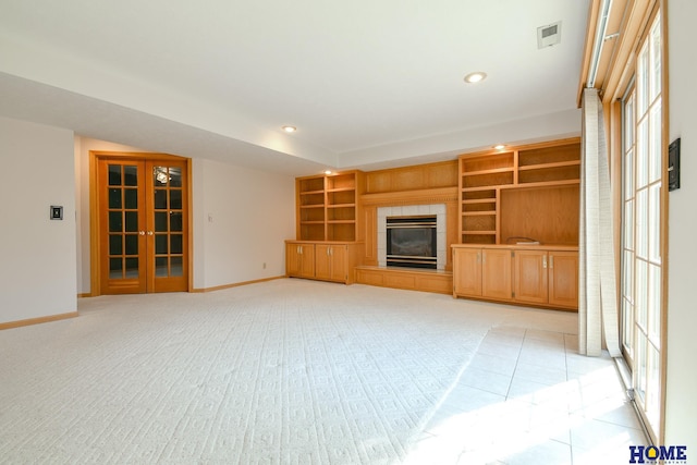 unfurnished living room with recessed lighting, french doors, baseboards, and a tile fireplace