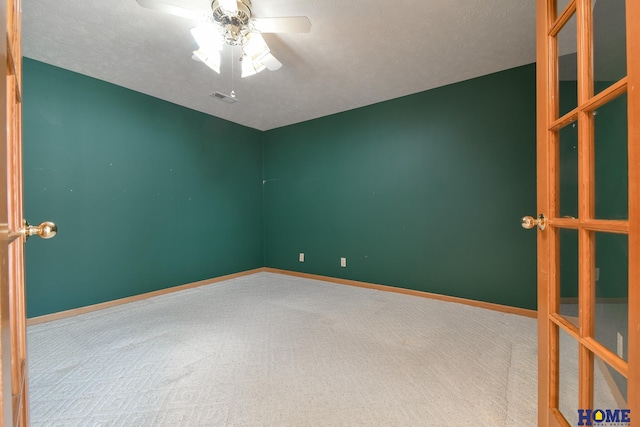 carpeted spare room featuring visible vents, baseboards, a textured ceiling, and a ceiling fan