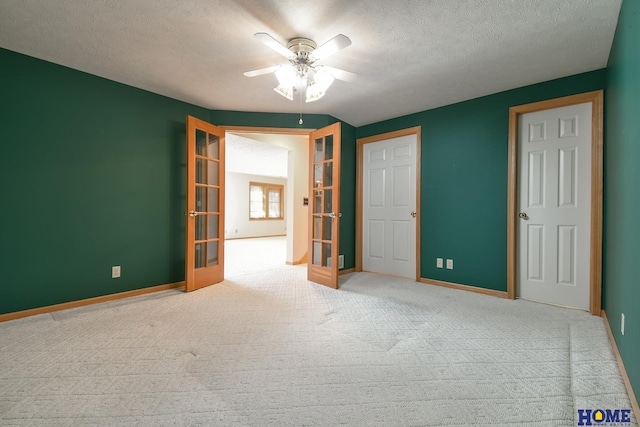 carpeted empty room featuring a ceiling fan, french doors, baseboards, and a textured ceiling