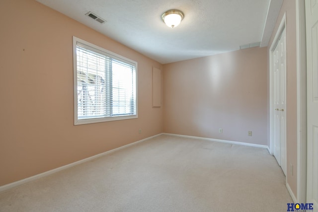 unfurnished bedroom featuring visible vents, baseboards, light colored carpet, a closet, and a textured ceiling